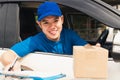 Delivery man courier wear uniform in the car hold documents clipboard hand over to customer to signing Royalty Free Stock Photo