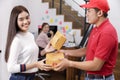 Delivery man delivering package to homeowner. Woman accepting a delivery of boxes from deliveryman. Delivery man wear red uniform Royalty Free Stock Photo