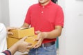 Delivery man delivering package to homeowner. Woman hand accepting a delivery of boxes from deliveryman. Delivery man wear red Royalty Free Stock Photo