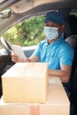 Delivery man driver wearing protective face mask holding digital tablet looking at camera with blurred cardboard boxes on van seat