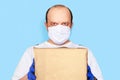 Delivery man employee face mask gloves hold mockup cardboard box isolated on blue.