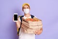Delivery man employee wearing protective mask holding food order pizza boxes and showing mobile phone with blank screen, isolated Royalty Free Stock Photo