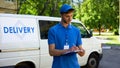 Delivery man filling parcel blank near company van, postal service, shipment Royalty Free Stock Photo