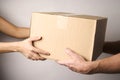 Delivery man giving cardboard box to female hand