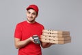 Delivery man giving hold food order pizza boxes isolated on grey background. Professional male pizzaman employee in red Royalty Free Stock Photo