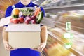 Delivery man hand holding paper box package in blue uniform and icon media symbol on grocery background. Delivery service Royalty Free Stock Photo