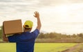 Delivery man holding brown parcel or cardboard boxes and delivery to customer at countryside and view of rice field