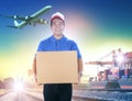 delivery man holding card box toothy smiling face against shipping port and cargo plane flying background Royalty Free Stock Photo