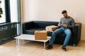 Delivery man holding using payment POS terminal waiting customer, sitting on sofa with boxes pizza and cardboard box Royalty Free Stock Photo