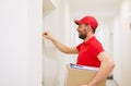 Delivery man with parcel box knocking on door