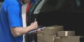 Delivery man preparing parcel box to customer while checking orders on tablet