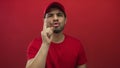 Delivery man in red cap scowls and points finger at camera in red studio space challenging viewer; duty urgency Royalty Free Stock Photo