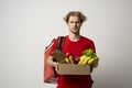 Delivery man in red uniform delivering food, groceries, vegetables, drinks in a paper box to a client at home. Online Royalty Free Stock Photo