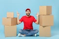 Delivery man in red uniform isolated on blue background, studio portrait. Male employee in cap t-shirt print working as