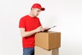 Delivery man in red uniform isolated on white background. Male courier in cap, t-shirt holding pen, clipboard with Royalty Free Stock Photo