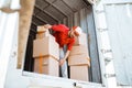 delivery man in red unloads several boxes from a container