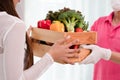 Delivery man sending wooden box of fresh organic