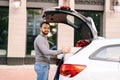 Delivery man standing near car, festive white box with beautiful red bow at truck, looking at camera Royalty Free Stock Photo