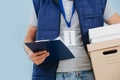 Delivery man in uniform is holding parcel cardboard boxes over blue background. Royalty Free Stock Photo