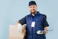 Delivery man in uniform holding signing form while leaning arm on a box