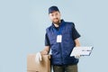 Delivery man in uniform holding signing form while leaning arm on a box