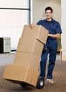 Delivery man in uniform pushing stack of boxes