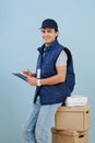 Delivery man in uniform is seating on a stack of parcel cardboard boxes Royalty Free Stock Photo