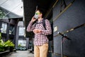 Delivery man uses smart phone while waiting customer at the entrance of house, uses alternative transport electric scooter, Royalty Free Stock Photo