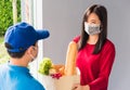 Delivery man wear protective face mask making grocery giving fresh food to woman customer Royalty Free Stock Photo