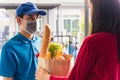 Delivery man wear protective face mask making grocery giving fresh food to woman customer Royalty Free Stock Photo