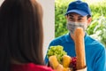 Delivery man wear protective face mask making grocery giving fresh food to woman customer Royalty Free Stock Photo