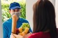 Delivery man wear protective face mask making grocery giving fresh food to woman customer Royalty Free Stock Photo