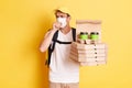 Delivery man wearing protective mask, holding pizza boxes and takeaway coffee, courier working during flu epidemic, catching cold Royalty Free Stock Photo