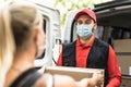 Delivery man at work wearing face mask - Young woman receiving an order from courier express Royalty Free Stock Photo