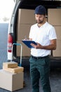 Delivery man writing on clipboard while standing next to his van Royalty Free Stock Photo