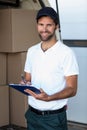 Delivery man writing on clipboard while standing next to his van Royalty Free Stock Photo