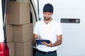 Delivery man writing on clipboard while standing next to his van Royalty Free Stock Photo