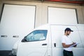 Delivery man writing on clipboard while standing next to his van Royalty Free Stock Photo