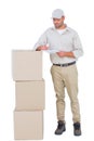 Delivery man writing on clipboard while standing by stacked boxes Royalty Free Stock Photo