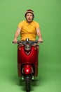 Delivery man in yellow uniform and helmet on scooter on green