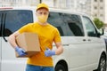 Delivery Man in yellow uniform medical mask and gloves holds a package. Safety delivery service covid-19 pandemic