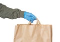 Delivery person hand wearing rubber glove holding paper bag isolated on white background. Safe shopping Royalty Free Stock Photo