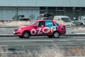 Delivery pink car of the Russian online store Ozon. Side view of car with Ozon Express logo. Courier driving on highway city road