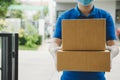 Delivery service man in blue uniform waiting for sending parcel post box to customer at door home Royalty Free Stock Photo