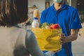 Delivery service man with protection face mask in blue uniform holding fresh food set bag for customer Royalty Free Stock Photo
