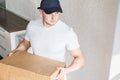 Delivery strong, muscular man loading cardboard boxes for moving to an apartment. professional worker of transportation