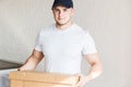 Delivery strong, muscular man loading cardboard boxes for moving to an apartment. professional worker of transportation