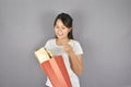 Delivery woman in red uniform holding present red gift box package on grey background Royalty Free Stock Photo