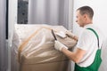 A delivery worker checks the buyer`s data on a large box with goods