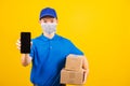 Delivery worker man wearing face mask protective show front black screen of smart mobile phone Royalty Free Stock Photo